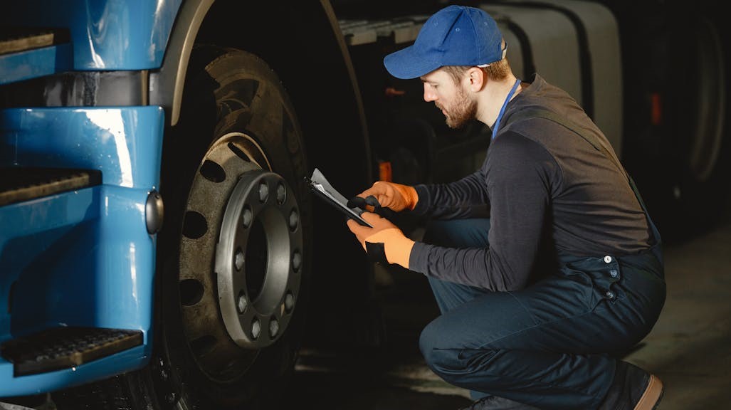 A mechanic is fixing a car engine in a garage, using tools and working carefully